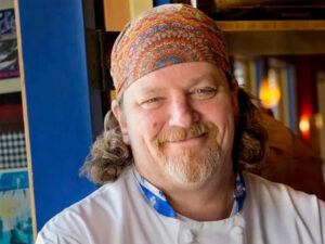 Smiling portrait of Bill Ranniger wearing a colorful beanie